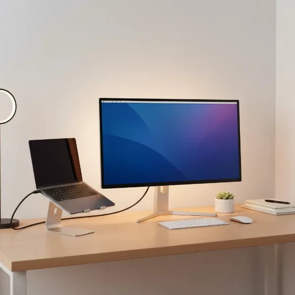 A MacBook Pro connected to a sleek USB-C monitor on a modern desk setup with minimal clutter, highlighting single-cable convenience.