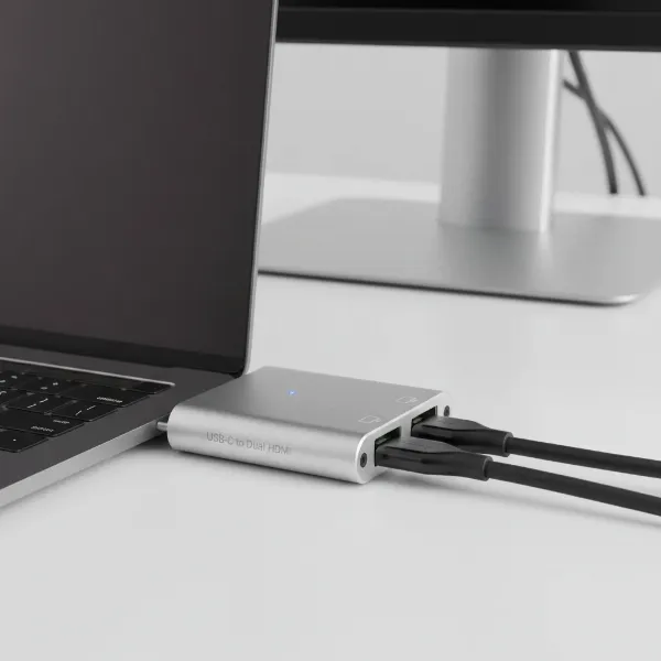 A compact USB-C to dual HDMI/DisplayPort adapter connecting to a laptop, facilitating two external displays.